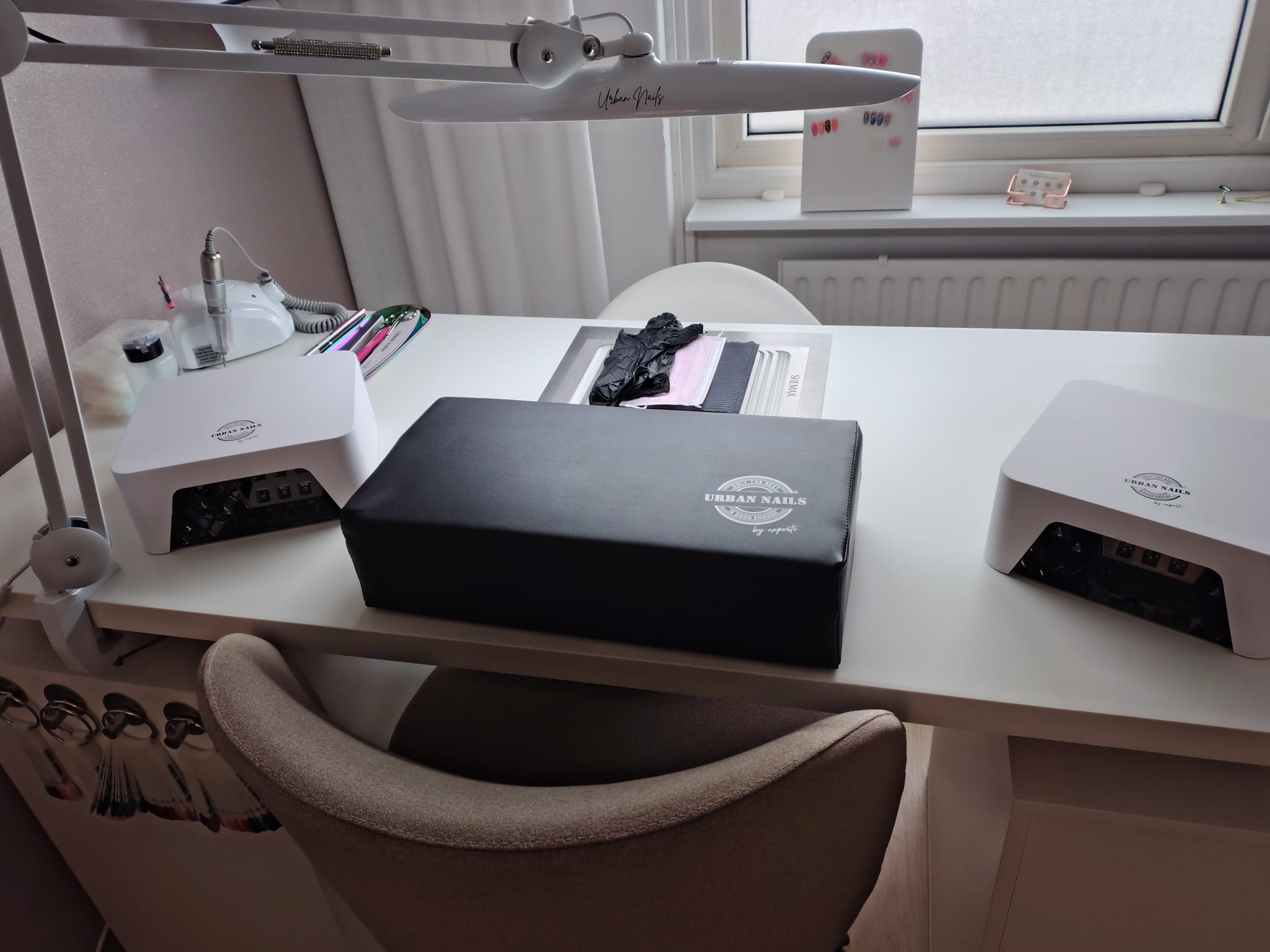 De werktafel in de nagelstudio met lamp, uv-lampen en armsteun bij het raam