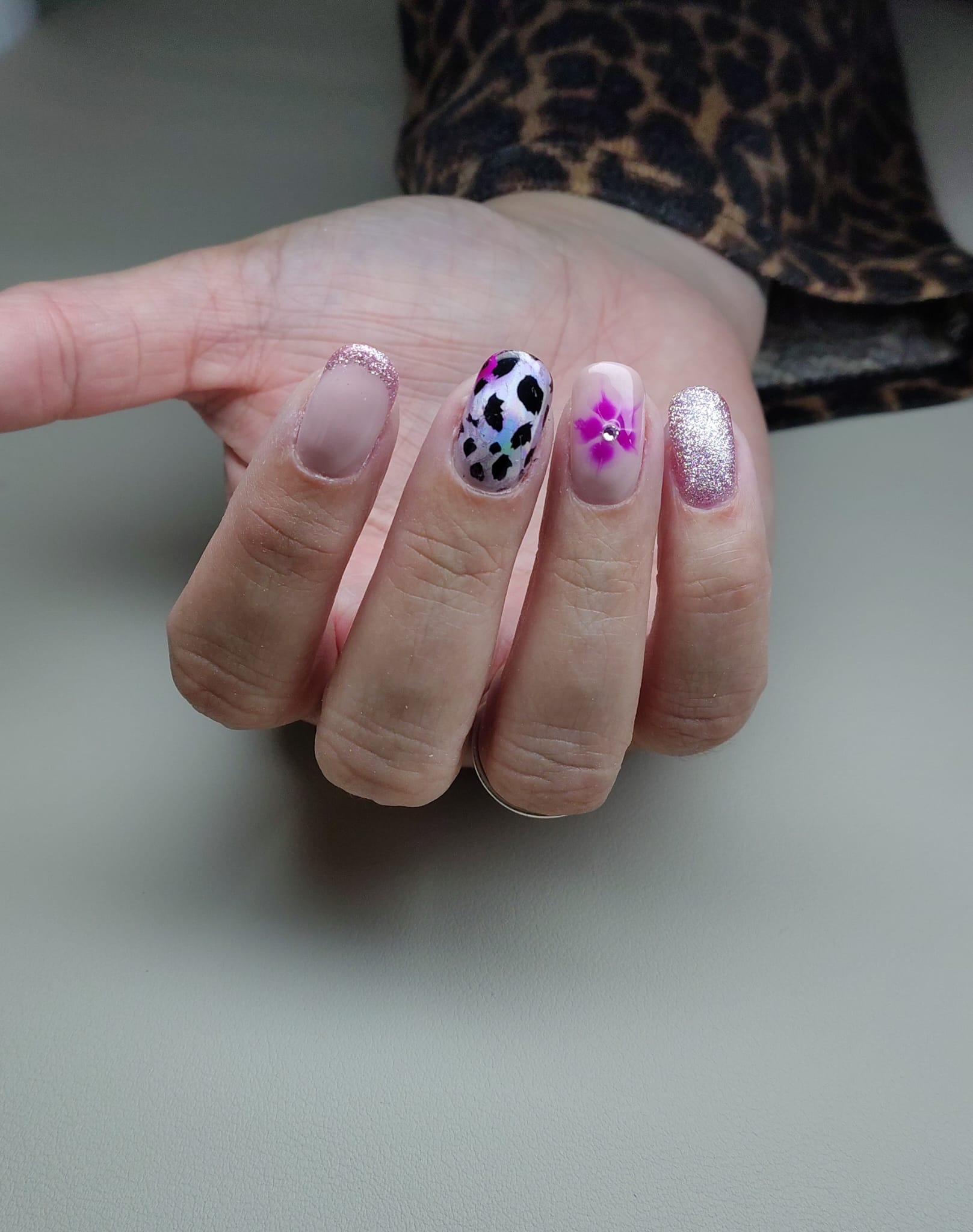 Nail art met koeienprint, een roze bloemetje en glitter
