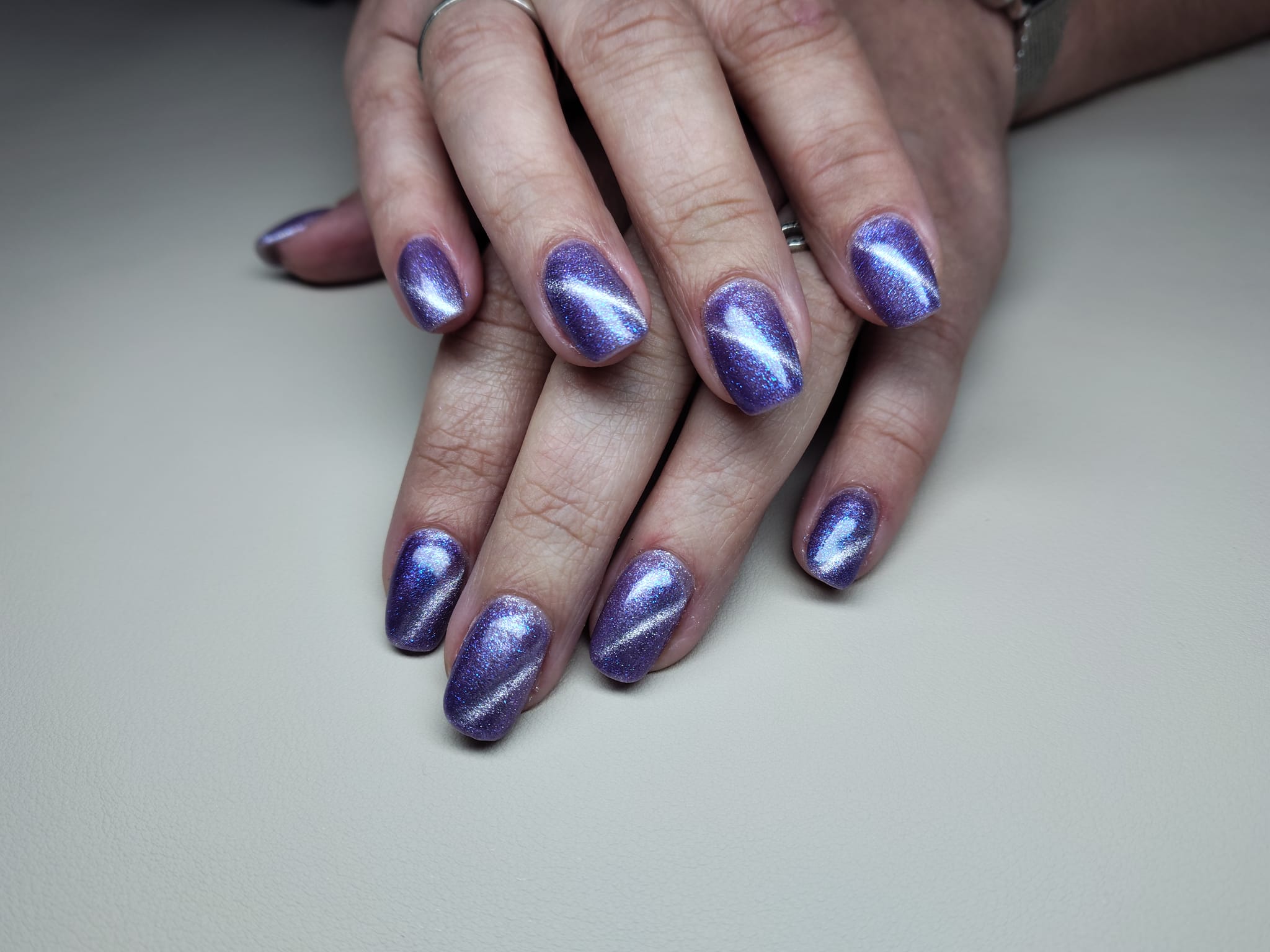 Handen met paarse cat-eye gelpolish